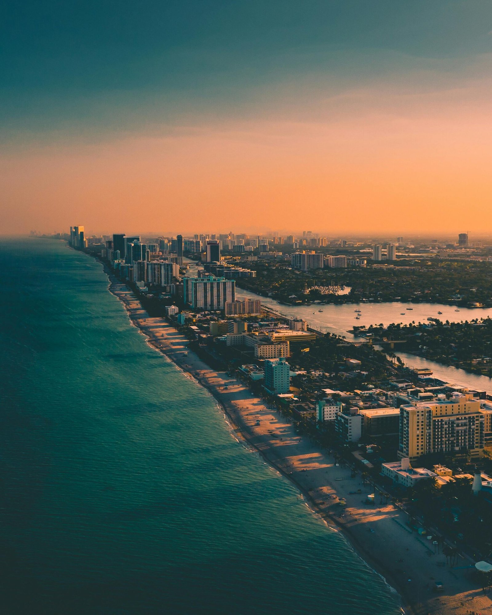 Dramatic aerial view of city skyline meeting the ocean at sunset.